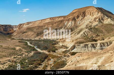 Ein einziger Tourbus auf der Straße zum Nationalpark ein avdat in israel mit dem Canyon und den Bergen im Hintergrund und dem bachbett nahal zin Stockfoto