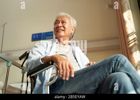 Asiatischer alter Mann sitzt im Rollstuhl im Pflegeheim oder in der Krankenstation und sieht glücklich und zufrieden aus Stockfoto