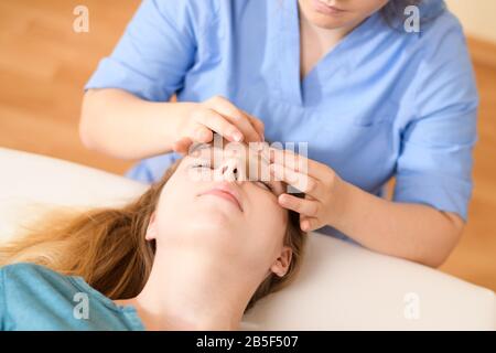 Schöne junge kaukasische Frau mit Gesichtsmassage im Spa-Salon. Entspannende Frau mit Gesichtsmassage im Spa. Stockfoto