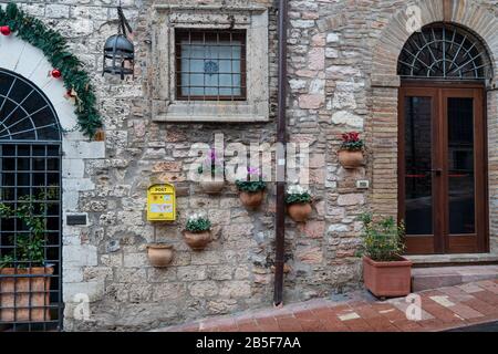 Assisi, UMBRIEN, ITALIEN - 31. Januar 2020: Eine Gebäudemauer in der Straße der Altstadt von Assisi. Fenster und Türen sind mit dekorativen en ausgeführt Stockfoto