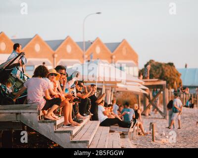 Einige australische Einheimische sitzen auf einigen Stufen neben dem Strand in Australien Stockfoto