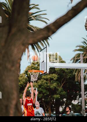 Einige australische Einheimische spielen eine Basketballspiel, umgeben von Palmen in Australien Stockfoto