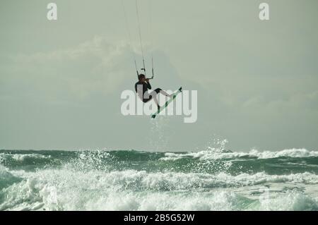 Kitesurfer, der in rauer See bei Lacanau-Océan, Frankreich, über Wellen springt und durch die Luft fliegt Stockfoto