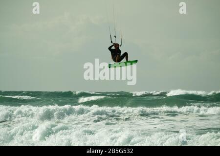 Kitesurfer, der in rauer See bei Lacanau-Océan, Frankreich, über Wellen springt und durch die Luft fliegt Stockfoto