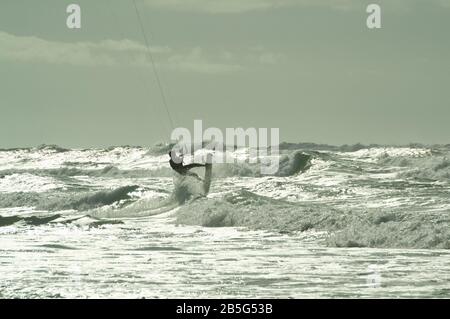 Kitesurfer, der in rauer See bei Lacanau-Océan, Frankreich, über Wellen springt Stockfoto