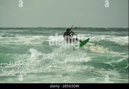 Kitesurfer, der in rauer See bei Lacanau-Océan, Frankreich, über Wellen springt Stockfoto