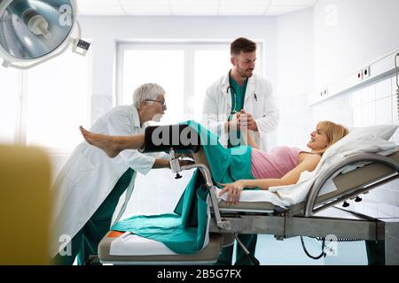 In dem Krankenhaus treibt die Frau in der Arbeit die Geburt voran, Geburtshelfer helfen Stockfoto