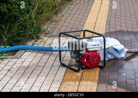 Die benzinbetriebene Zentrifugalpumpe pumpt Abwasser aus einem überschwemmten Bereich Stockfoto