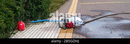 Die benzinbetriebene Zentrifugalpumpe pumpt Abwasser aus einem überschwemmten Bereich Stockfoto