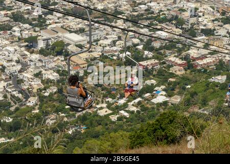 ANACAPRI, Capri, Italien - AUGUST 2019: Menschen auf Reisen ein Sessellift auf den Berg hinauf auf den Gipfel des Monte Solaro oben Anacapri und nach unten Stockfoto