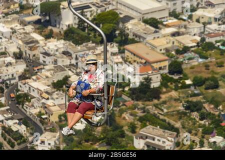 ANACAPRI, Capri, Italien - AUGUST 2019: Person auf einem Sessellift fahren den Berg hinauf auf den Gipfel des Monte Solaro oben Anacapri und nach unten Stockfoto