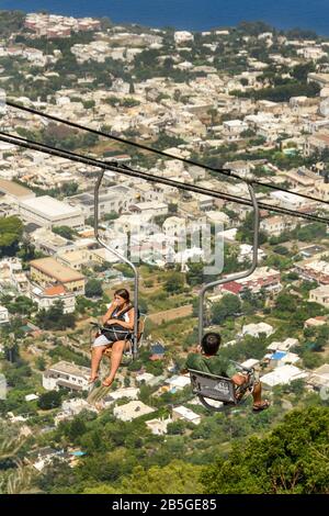 Anacapri, INSEL CAPRI, ITALIEN - AUGUST 2019: Besucher auf einem Sessellift, der zum Gipfel des Solaro oberhalb von Anacapri fährt Stockfoto