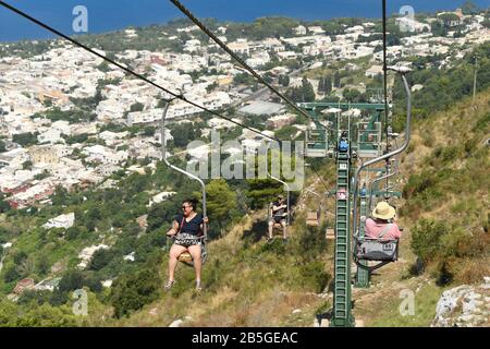 Anacapri, INSEL CAPRI, ITALIEN - AUGUST 2019: Besucher auf einem Sessellift, der zum Gipfel des Solaro oberhalb von Anacapri fährt Stockfoto