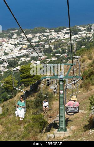 Anacapri, INSEL CAPRI, ITALIEN - AUGUST 2019: Besucher auf einem Sessellift, der zum Gipfel des Solaro oberhalb von Anacapri fährt Stockfoto