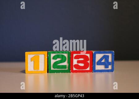 Horizontaler Stapel von Spielzeugblöcken aus farbigem Alphabet aus Holz auf blauem Hintergrund Stockfoto