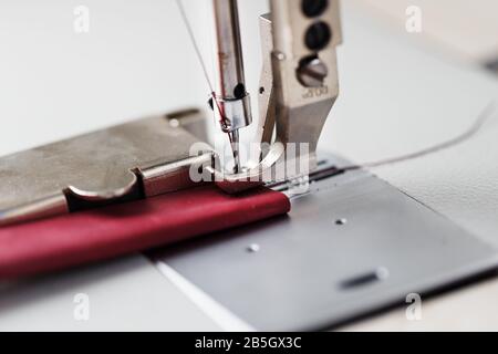 Ein Lederhandwerker stellt in seinem Laden Lederwaren an einer Nähmaschine her. Handgefertigte Arbeit. Nahaufnahme. Stockfoto