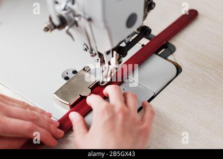 Ein Lederhandwerker stellt in seinem Laden Lederwaren an einer Nähmaschine her. Handgefertigte Arbeit. Nahaufnahme. Stockfoto