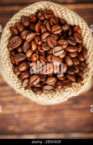 Frisch gerösteter aromatischer Kaffee in einer Burlap Tasche auf Holzgrund. Kaffeebohnen, für Getränke Stockfoto