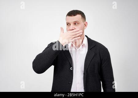Porträt des Menschen mit der Hand über den Mund, die beiseite blickt, verblüfft und sprachlos Stockfoto