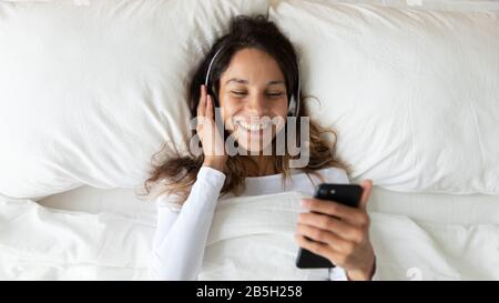 Draufsicht über lächelnde Mädchen hören Musik auf dem Handy Stockfoto