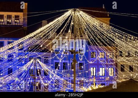 Altstadt von Warschau in Polen, abstrakte Weihnachtsfeiertagsbeleuchtung, leuchtende Lichtgarlands mit historischen Häusern im Hintergrund Stockfoto