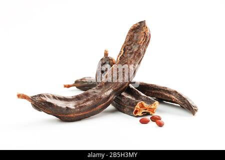 Karob-Karob-Früchte und Samen auf weißem Hintergrund. Isolieren. Biobohnen, eine gesunde Alternative zum Kakao. Stockfoto