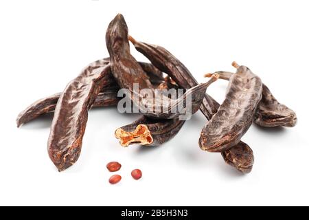 Karob-Karob-Früchte und Samen auf weißem Hintergrund. Isolieren. Biobohnen, eine gesunde Alternative zum Kakao. Stockfoto