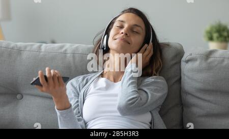 Junge Frau in Ohrhörern genießen guten Klang Stockfoto