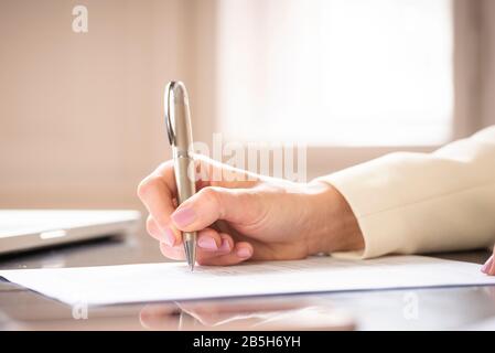 Nahaufnahme der Hand der Geschäftsfrau beim Ausfüllen des Formulars. Stockfoto