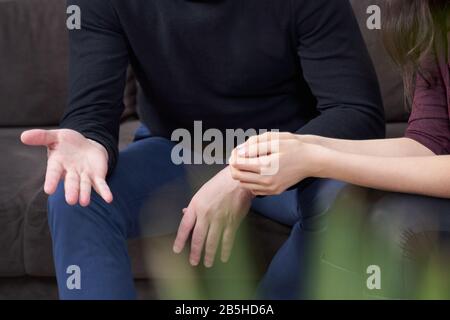 Beschnittenes Bild von Mann und Frau, die sprechen, während sie auf einer Couch sitzen Stockfoto