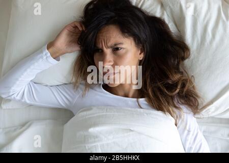 Ängstliches, tausendjähriges Mädchen, das im Bett liegt und an Schlaflosigkeit leidet Stockfoto