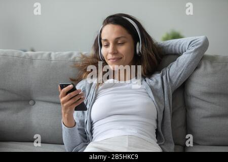 Tausendjährige Mädchen in Kopfhörern genießen Musik auf dem Smartphone Stockfoto