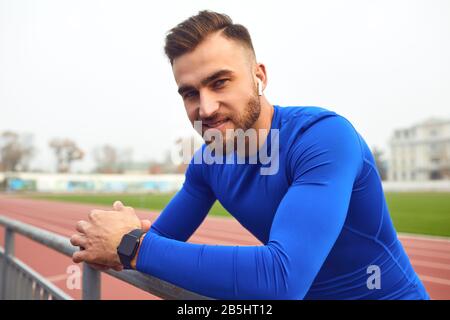Ein Sportzentrum in blauer Kleidung lächelt, während er im Nebel das Stadion betrachtet. Stockfoto