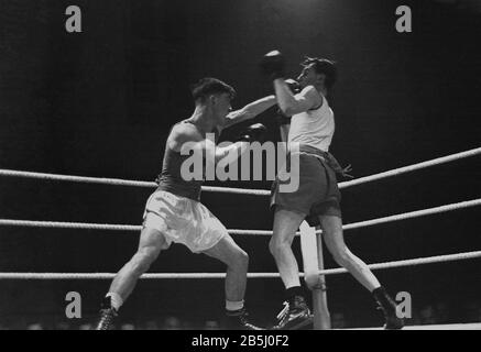 1950er Jahre, historisches Amateurboxen dieser Ära, zwei junge männliche Boxer kämpfen in einem Ring, einer wirft mit der linken Hand, ein Schlag ins Gesicht des anderen, England, Großbritannien. Stockfoto