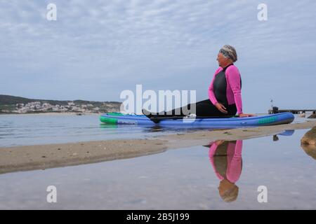 Foz Do Arelho, Portugal, 8. März 2020 - eine ältere Frau, die auf einem SUP-Paddleboard sitzt Stockfoto