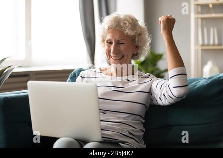 Aufgeregte Frau entspannen Sie sich mit dem Laptop Lesen Sie fantastische Nachrichten Stockfoto