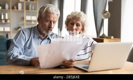 Ältere Ehegatten und Ehefrau lesen Dokumente bezahlen Rechnungen online Stockfoto