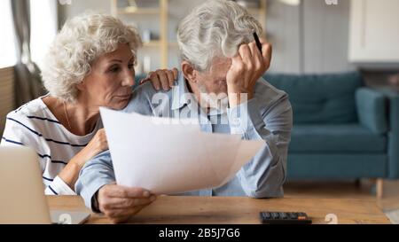 In Verdruss geratene ältere Ehepaare machen sich mit den Ausgaben für die Haushaltsfinanzierung Sorgen Stockfoto