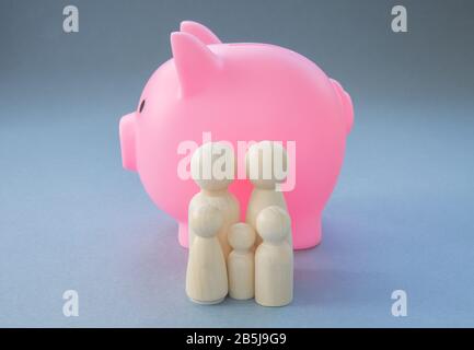 Ein Konzeptbild einer Familie, die vor einer großen, rosafarbenen Piggy Bank steht, die die Bank von Mutter und Vater mit Kopierraum repräsentiert Stockfoto