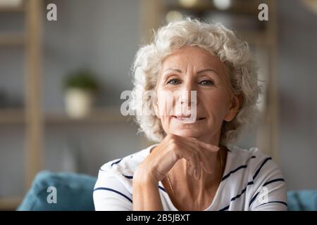 Portrait der optimistischen älteren Frau, die sich zu Hause entspannt Stockfoto