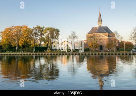 Malerische Aussicht auf eine historische Kirche und Bäume mit Herbstblattfarbe entlang des Rheins, Holland. Stockfoto