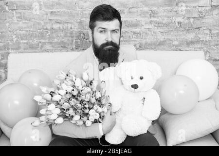 Mann gut gepflegt Verschleiß tuxedo Bow Tie halten Blumen Tulpen Bouquet und großen Teddybären Spielzeug. Laden Sie dating. Romantisches Geschenk. Romantischen Mann. Macho fertig, romantisches Date. Warten auf Darling. Stockfoto