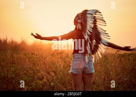 Wunderschönes indianisches Mädchen auf dem Feld in der Landschaft bei Sonnenuntergang. Stockfoto