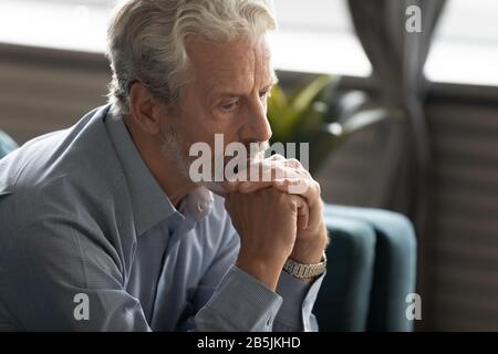 Unglücklicher älterer Mann blickt in die Ferne und denkt an die Vergangenheit Stockfoto