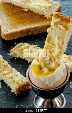 Weich gekochtes Ei mit Toastscheiben und Butter, getaucht im Frühstückskonzept Stockfoto