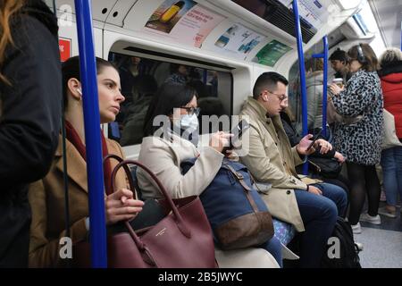 Pendler der Londoner U-Bahn tragen Gesichtsmasken zum Schutz vor Coronavirus Übertragung. Stockfoto