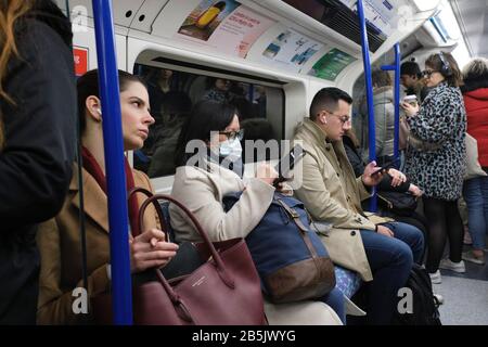 Pendler der Londoner U-Bahn tragen Gesichtsmasken zum Schutz vor Coronavirus Übertragung. Stockfoto