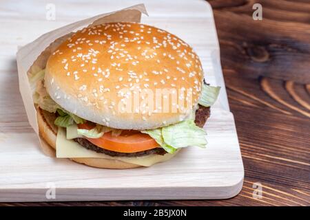 Burger in Papier und auf einer Lichttafel aus gebranntem Holz Stockfoto