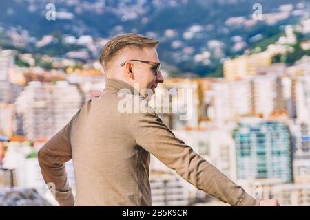 Junger Mann mit Panoramablick vom Prinzenpalast in Monte Carlo an der französischen Riviera am Seepier in Monaco gegen Luxuswohnungen und Hi Stockfoto