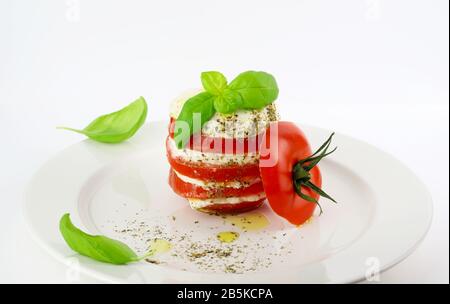Konzept der italienischen Küche. Köstlicher Capresse-Salat mit reifen Tomaten und Mozzarella-Käse mit frischen Basilikumblättern. Weißer Hintergrund. Stockfoto